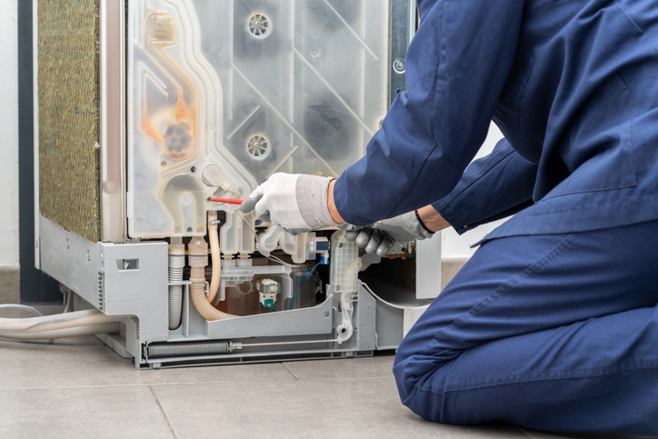 Shot of a young man repairing dishwasher in a home